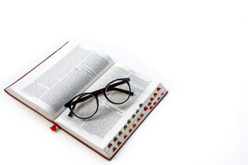 Open holy bible in bahasa Indonesia on white background with glasses