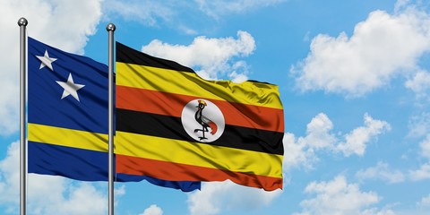 Curacao and Uganda flag waving in the wind against white cloudy blue sky together. Diplomacy concept, international relations.