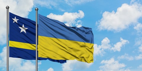 Curacao and Ukraine flag waving in the wind against white cloudy blue sky together. Diplomacy concept, international relations.