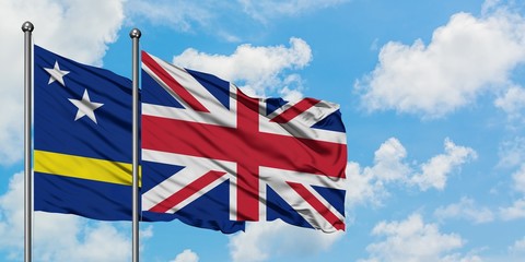 Curacao and United Kingdom flag waving in the wind against white cloudy blue sky together. Diplomacy concept, international relations.