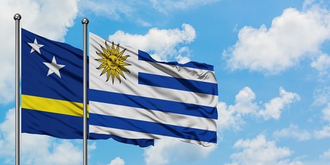 Curacao and Uruguay flag waving in the wind against white cloudy blue sky together. Diplomacy concept, international relations.