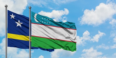 Curacao and Uzbekistan flag waving in the wind against white cloudy blue sky together. Diplomacy concept, international relations.