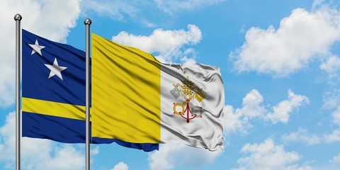 Curacao and Vatican City flag waving in the wind against white cloudy blue sky together. Diplomacy concept, international relations.
