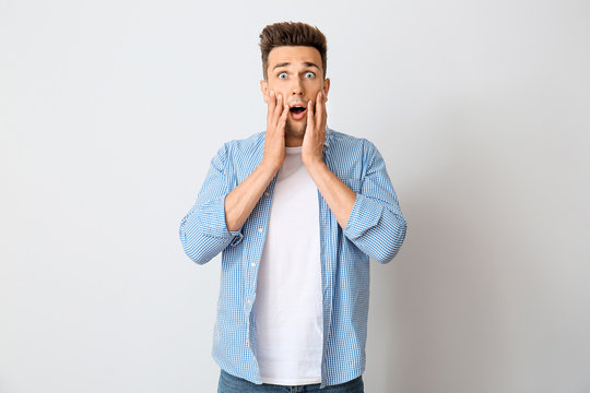 Shocked young man on light background
