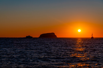 A vibrant sunset with Boats on the Aegean Sea in the Greek Islands