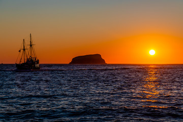 Fototapeta na wymiar A vibrant sunset with Boats on the Aegean Sea in the Greek Islands