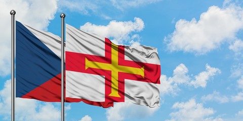 Czech Republic and Guernsey flag waving in the wind against white cloudy blue sky together. Diplomacy concept, international relations.