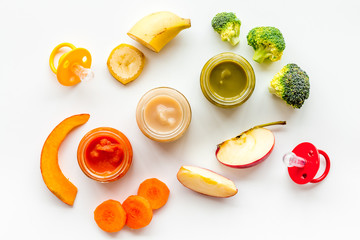 Baby food. Colorful puree in glass jars near vegetables and fruits on white background top view