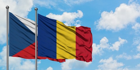 Czech Republic and Romania flag waving in the wind against white cloudy blue sky together....