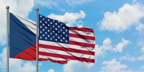 Czech Republic and United States flag waving in the wind against white cloudy blue sky together. Diplomacy concept, international relations.