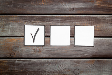 Check mark in check-box on dark wooden background top view copy space