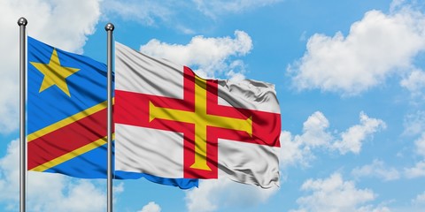 Congo and Guernsey flag waving in the wind against white cloudy blue sky together. Diplomacy concept, international relations.