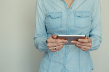 Image of a young woman working on a tablet computer at home on a background of light wall