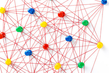 Network with colorful pins and string,  linked together with string on a white background suggesting a network of connections.