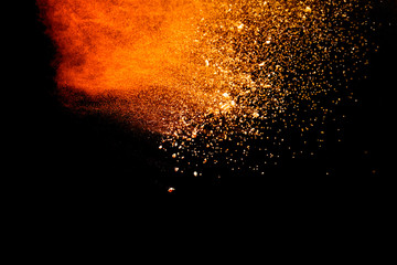Abstract orange powder explosion isolated on black background.