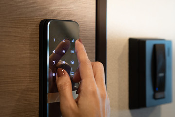 Closeup of a woman's finger entering password code on the smart digital touch screen keypad entry door lock in front of the room. Self Check-in, Airbnb, Modern security, Keyless, Temporary codes. - obrazy, fototapety, plakaty