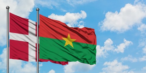 Denmark and Burkina Faso flag waving in the wind against white cloudy blue sky together. Diplomacy concept, international relations.
