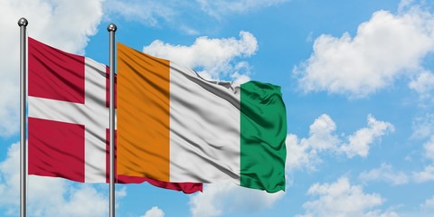Denmark and Cote D'Ivoire flag waving in the wind against white cloudy blue sky together. Diplomacy concept, international relations.