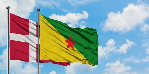 Denmark and French Guiana flag waving in the wind against white cloudy blue sky together. Diplomacy concept, international relations.