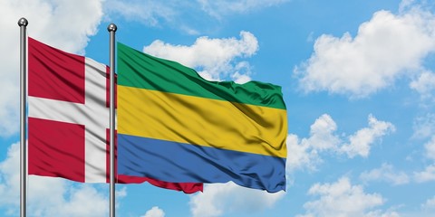 Denmark and Gabon flag waving in the wind against white cloudy blue sky together. Diplomacy concept, international relations.