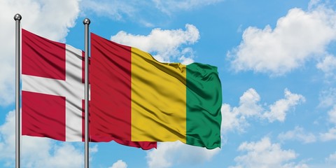 Denmark and Guinea flag waving in the wind against white cloudy blue sky together. Diplomacy concept, international relations.
