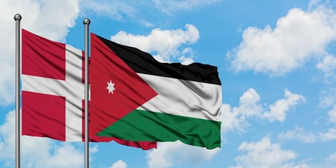 Denmark and Jordan flag waving in the wind against white cloudy blue sky together. Diplomacy concept, international relations.