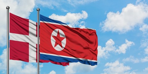 Denmark and North Korea flag waving in the wind against white cloudy blue sky together. Diplomacy concept, international relations.