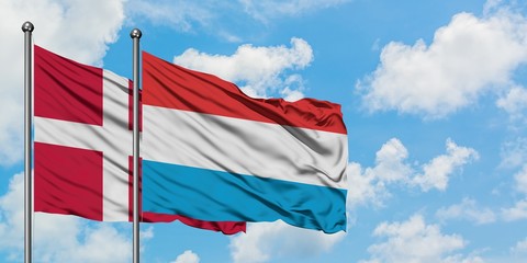 Denmark and Luxembourg flag waving in the wind against white cloudy blue sky together. Diplomacy concept, international relations.