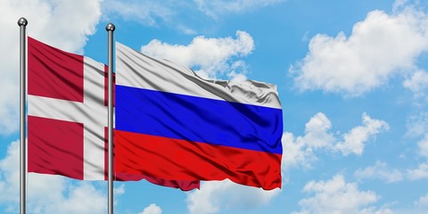 Denmark and Russia flag waving in the wind against white cloudy blue sky together. Diplomacy concept, international relations.