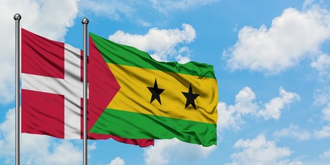 Denmark and Sao Tome And Principe flag waving in the wind against white cloudy blue sky together. Diplomacy concept, international relations.