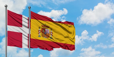 Denmark and Spain flag waving in the wind against white cloudy blue sky together. Diplomacy concept, international relations.