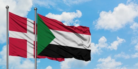 Denmark and Sudan flag waving in the wind against white cloudy blue sky together. Diplomacy concept, international relations.