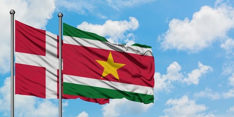 Denmark and Suriname flag waving in the wind against white cloudy blue sky together. Diplomacy concept, international relations.