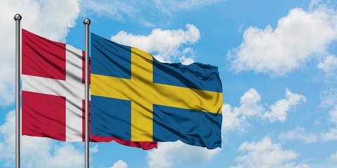 Denmark and Sweden flag waving in the wind against white cloudy blue sky together. Diplomacy concept, international relations.