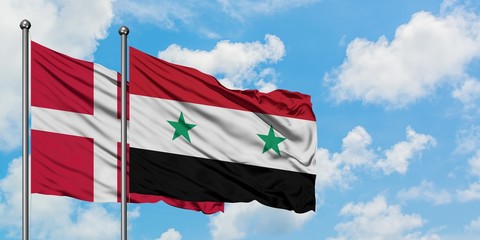 Denmark and Syria flag waving in the wind against white cloudy blue sky together. Diplomacy...