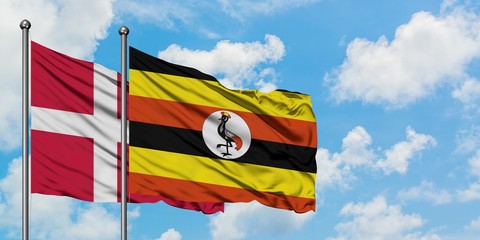 Denmark and Uganda flag waving in the wind against white cloudy blue sky together. Diplomacy concept, international relations.