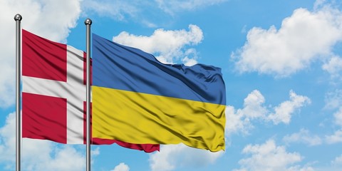 Denmark and Ukraine flag waving in the wind against white cloudy blue sky together. Diplomacy concept, international relations.