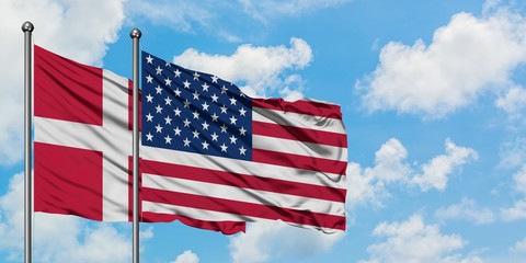 Denmark and United States flag waving in the wind against white cloudy blue sky together. Diplomacy concept, international relations.