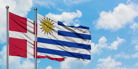 Denmark and Uruguay flag waving in the wind against white cloudy blue sky together. Diplomacy concept, international relations.