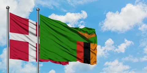 Denmark and Zambia flag waving in the wind against white cloudy blue sky together. Diplomacy concept, international relations.