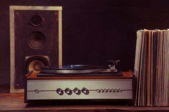 Vintage turntable audio column and vinyl records on a black background. Retro style