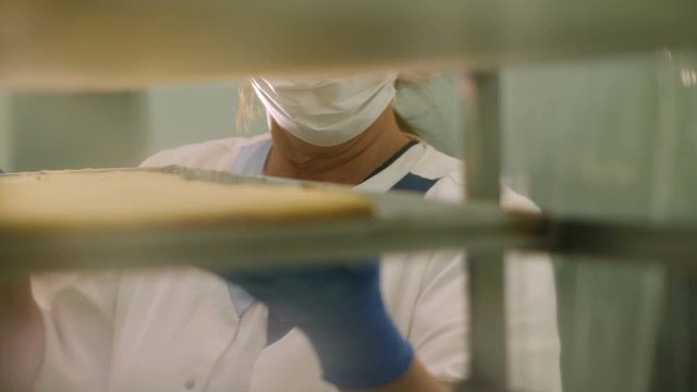 Baker putting a tray with fresh cakes on steel rack