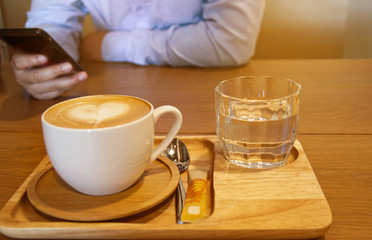A coffee cup in front of a man using a mobile phone.Business and technology concept.
