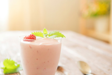 Pink yogurt with fresh strawberries on a old rustic wooden table in home interior