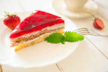Strawberry tart on plate on white wooden table