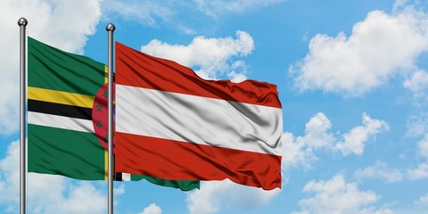 Dominica and Austria flag waving in the wind against white cloudy blue sky together. Diplomacy...