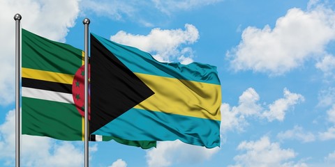Dominica and Bahamas flag waving in the wind against white cloudy blue sky together. Diplomacy...