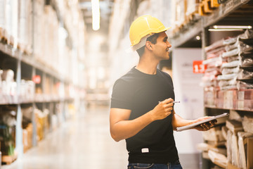 Smart Indian engineer man worker doing stocktaking of product management in cardboard box on shelves in warehouse. Factory physical inventory count.