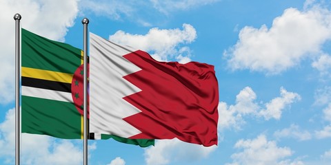 Dominica and Bahrain flag waving in the wind against white cloudy blue sky together. Diplomacy concept, international relations.