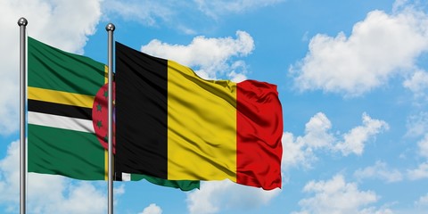 Dominica and Belgium flag waving in the wind against white cloudy blue sky together. Diplomacy...